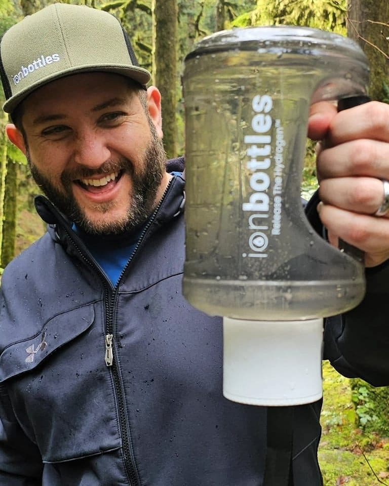 Bobby Samai holding an ionbottles jug in the woods