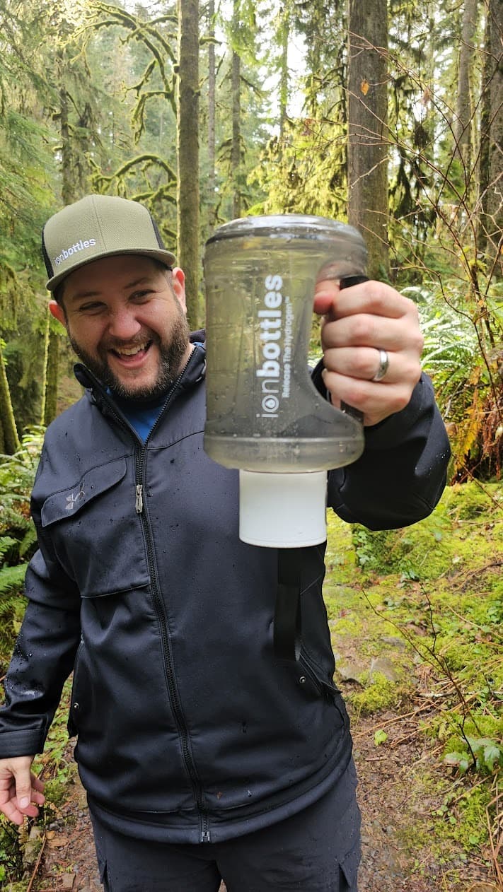 Bobby Samai, founder of ionbottles and EcomDada, in the woods holding an ionbottles jug
